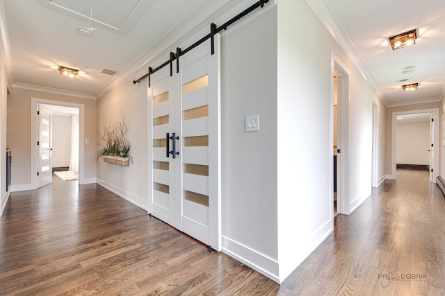 corridor featuring a barn door, crown molding, dark wood-style flooring, and attic access