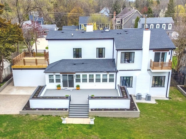 rear view of house featuring roof with shingles, central AC, and a patio