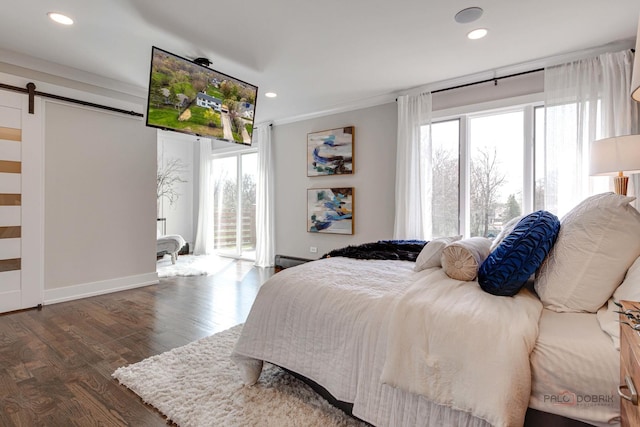 bedroom featuring a barn door, multiple windows, wood finished floors, recessed lighting, and baseboards