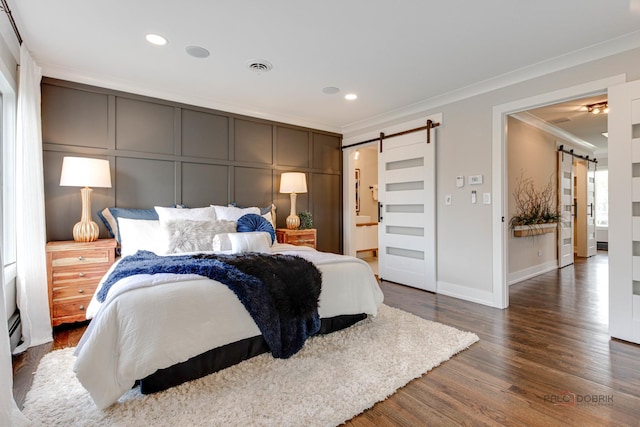 bedroom featuring a barn door, crown molding, dark wood finished floors, recessed lighting, and baseboards