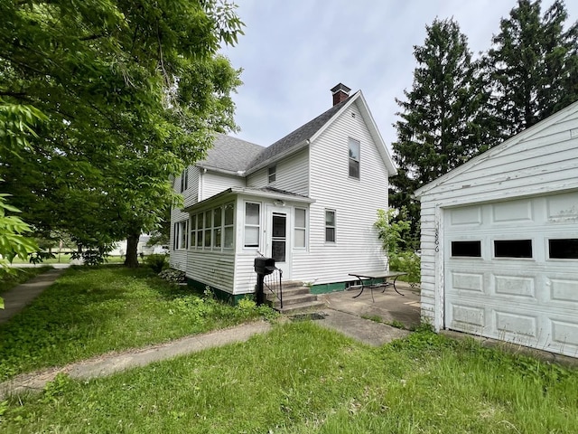 866 E Center St, Paxton, IL 60957 - view of property exterior featuring a chimney, roof with shingles, entry steps, a yard, and a garage