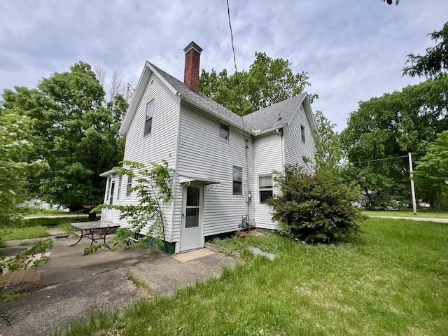 866 E Center St, Paxton, IL 60957 - view of property exterior with a chimney, a lawn, a patio area, and a shingled roof