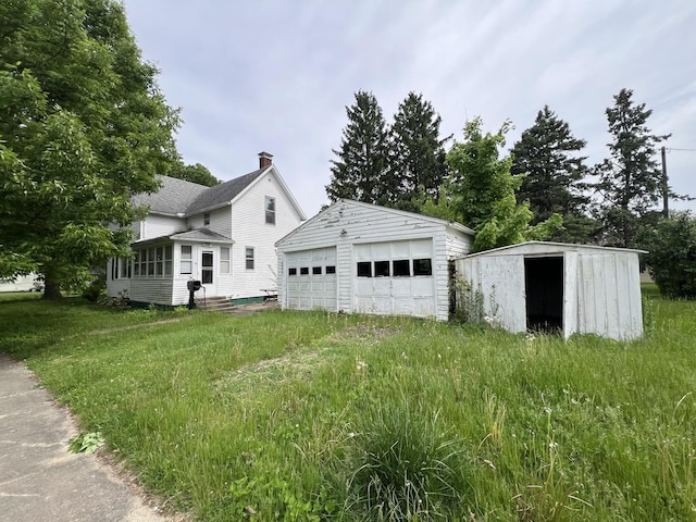 866 E Center St, Paxton, IL 60957 - view of home's exterior featuring an outbuilding, a chimney, a detached garage, and entry steps