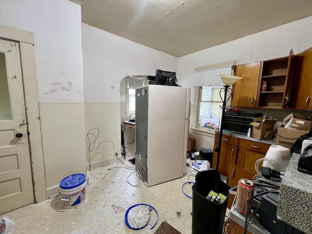 866 E Center St, Paxton, IL 60957 - kitchen featuring freestanding refrigerator, open shelves, brown cabinetry, unfinished concrete flooring, and light countertops