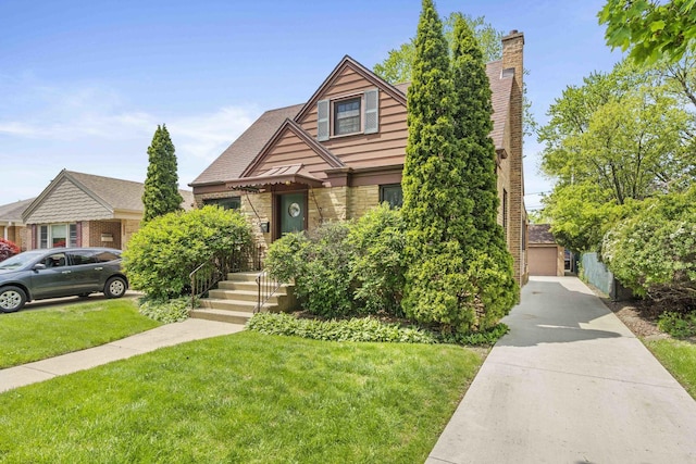 tudor home with a front lawn, stone siding, and a detached garage