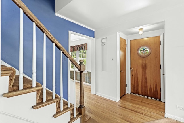 foyer featuring stairs, wood finished floors, and baseboards