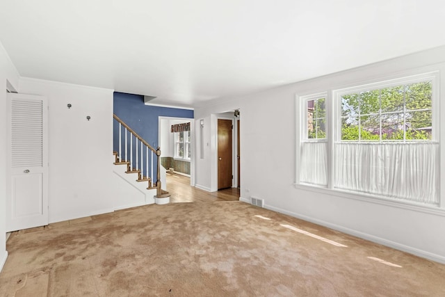 unfurnished living room with carpet floors, stairs, and baseboards
