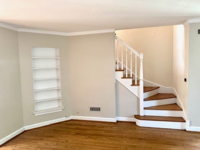 stairway with wood finished floors, crown molding, baseboards, and built in features