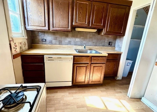 kitchen with white appliances, a sink, light countertops, and light wood-style flooring