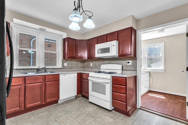 kitchen with white appliances, light countertops, a sink, decorative backsplash, and decorative light fixtures