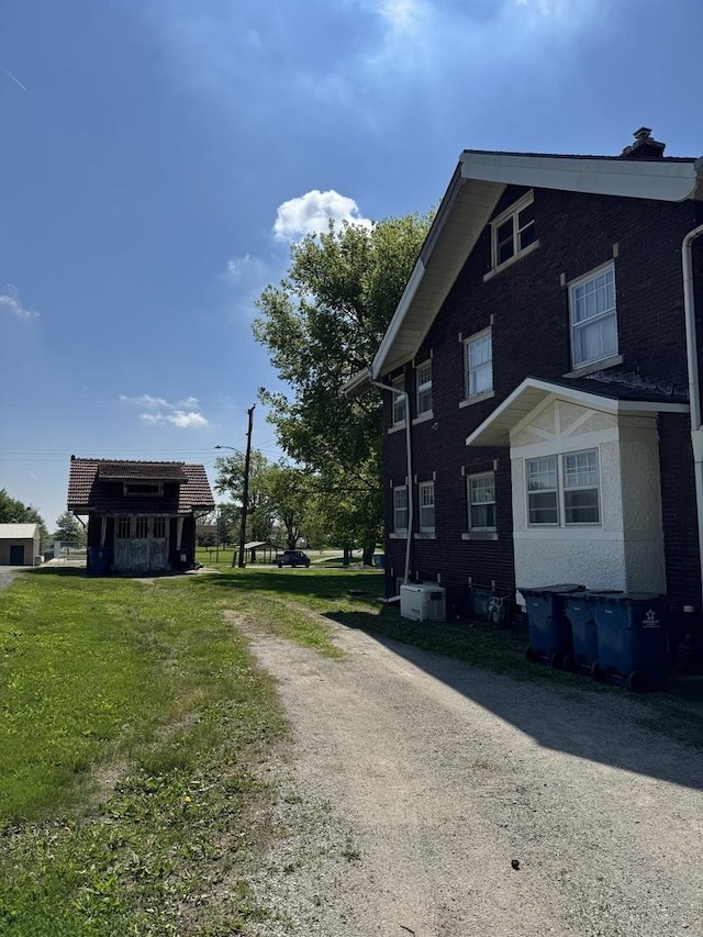 view of home's exterior featuring central AC, driveway, and a yard