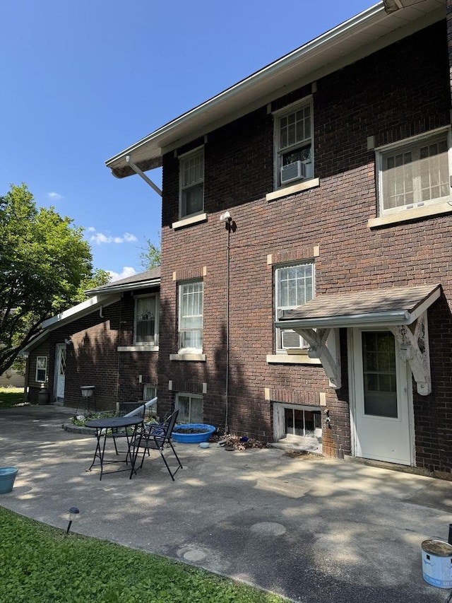 rear view of house with a patio, brick siding, and cooling unit