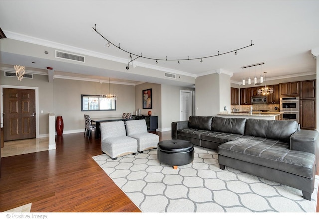 21 E Huron St Unit 3204, Chicago, IL 60611 - living room with a chandelier, rail lighting, wood finished floors, ornamental molding, and baseboards