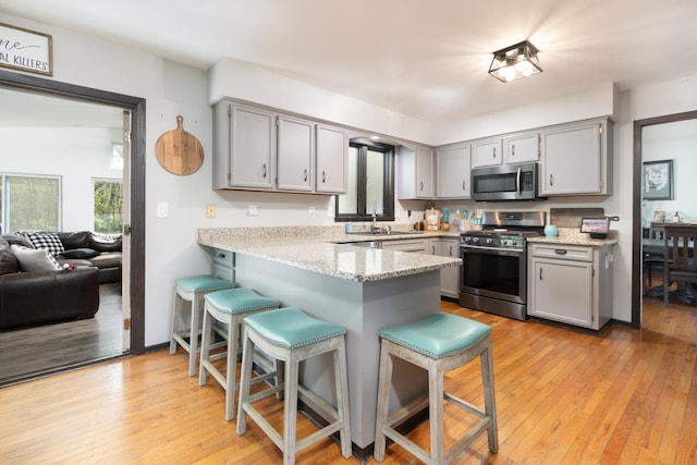 12367 Squirrel Tree Ln, Belvidere, IL 61008 - kitchen featuring appliances with stainless steel finishes, gray cabinets, a peninsula, and a kitchen breakfast bar