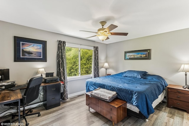bedroom with light wood-style floors, an office area, baseboards, and a ceiling fan