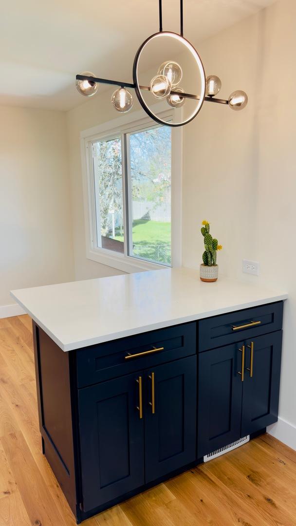 527 Northgate Rd, Lindenhurst, IL 60046 - kitchen with blue cabinets, a chandelier, light countertops, and light wood-style floors