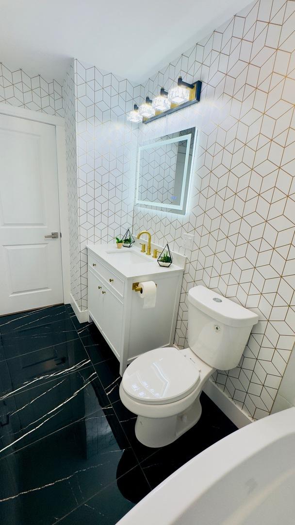 527 Northgate Rd, Lindenhurst, IL 60046 - half bath with tile walls, toilet, marble look tiles, and vanity
