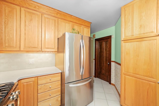 kitchen with stainless steel appliances, light brown cabinets, light tile patterned floors, light countertops, and backsplash