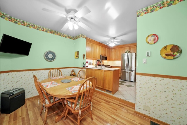 dining area with ceiling fan, wainscoting, light wood finished floors, and wallpapered walls