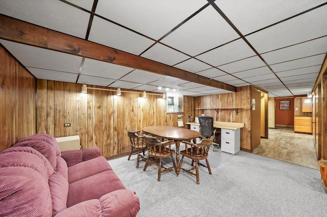 dining room with wood walls, carpet flooring, a paneled ceiling, and baseboards