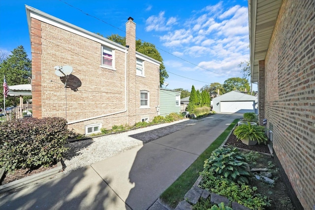 view of side of property with brick siding, a garage, an outdoor structure, and a chimney