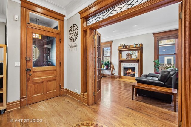 4752 N Beacon St, Chicago, IL 60613 - entryway with ornamental molding, light wood finished floors, a glass covered fireplace, and baseboards