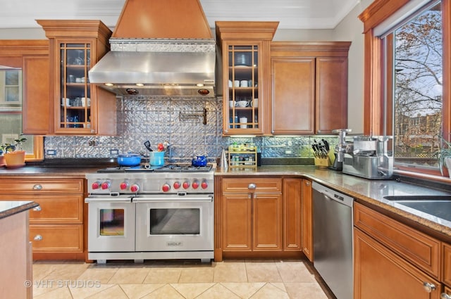 4752 N Beacon St, Chicago, IL 60613 - kitchen featuring stainless steel appliances, wall chimney exhaust hood, backsplash, and brown cabinetry