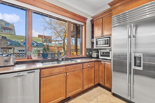 4752 N Beacon St, Chicago, IL 60613 - kitchen featuring built in appliances, a sink, brown cabinetry, and light tile patterned flooring