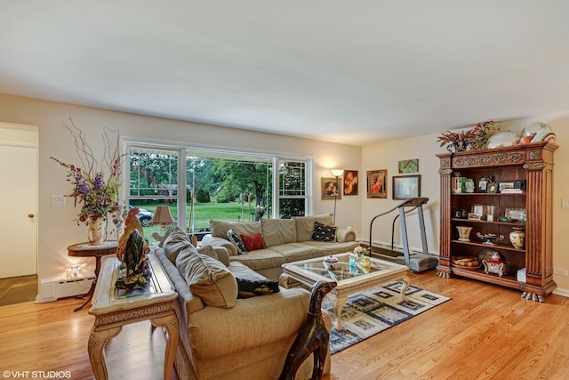 living room featuring light wood finished floors, a baseboard heating unit, and baseboards