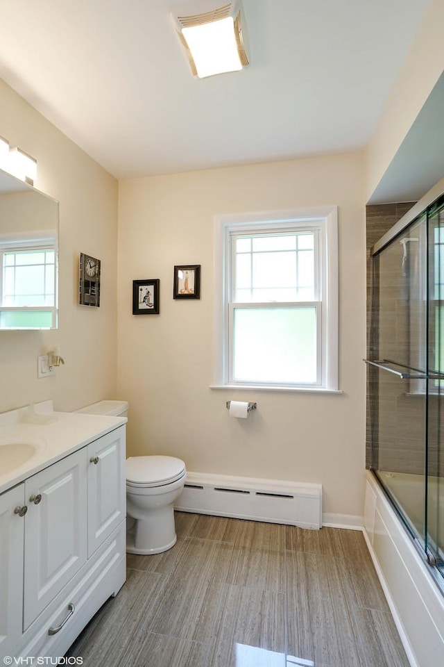 bathroom with a baseboard heating unit, plenty of natural light, vanity, and toilet