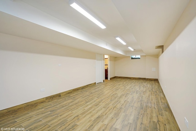 finished below grade area with light wood-style flooring and baseboards