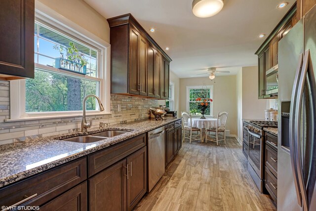 kitchen with stainless steel appliances, a sink, tasteful backsplash, and stone countertops