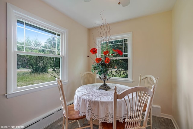 dining room featuring wood finished floors, baseboards, and a baseboard heating unit