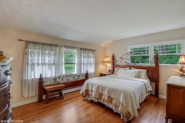 bedroom featuring wood finished floors, vaulted ceiling, and baseboards