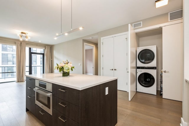1701 W Webster Ave Unit 611, Chicago, IL 60614 - kitchen with modern cabinets, estacked washer and dryer, light wood-type flooring, oven, and light countertops