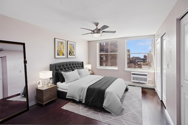 bedroom with a wall mounted AC, wood finished floors, baseboards, and a ceiling fan