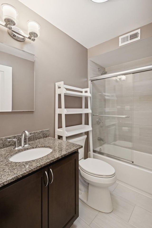 bathroom with toilet, vanity, tile patterned floors, and enclosed tub / shower combo