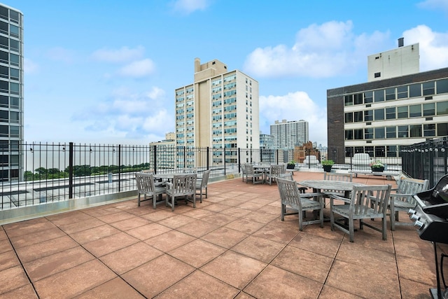 view of patio / terrace featuring outdoor dining area, a city view, and fence