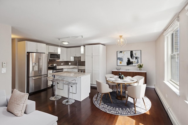 kitchen with appliances with stainless steel finishes, dark wood-type flooring, a sink, tasteful backsplash, and white cabinets
