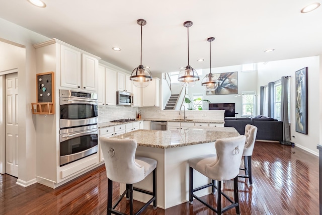 3080 Wickenden Ave, Elgin, IL 60124 - kitchen with stainless steel appliances, a sink, a kitchen bar, open floor plan, and dark wood-type flooring