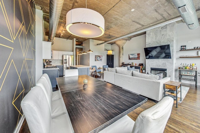 dining area with light wood-style floors, a fireplace, and ornate columns