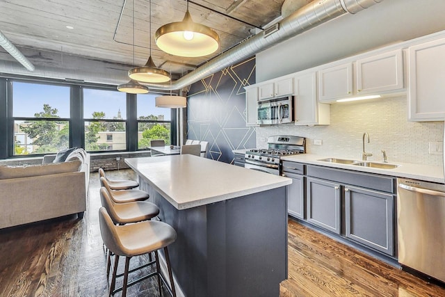 kitchen with stainless steel appliances, a sink, gray cabinetry, a center island, and tasteful backsplash