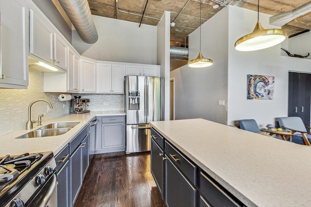 kitchen featuring appliances with stainless steel finishes, a sink, white cabinetry, dark wood-style floors, and decorative backsplash