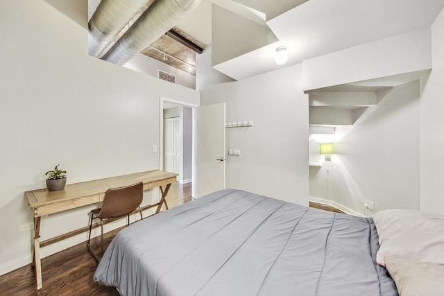 bedroom featuring wood finished floors, baseboards, and a high ceiling
