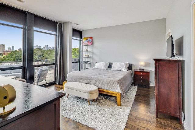 bedroom with access to exterior, expansive windows, a view of skyline, dark wood-style flooring, and baseboards
