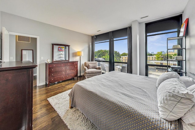 bedroom featuring access to exterior, wood finished floors, expansive windows, and baseboards