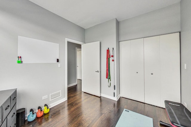 unfurnished bedroom featuring wood finished floors, baseboards, and a closet