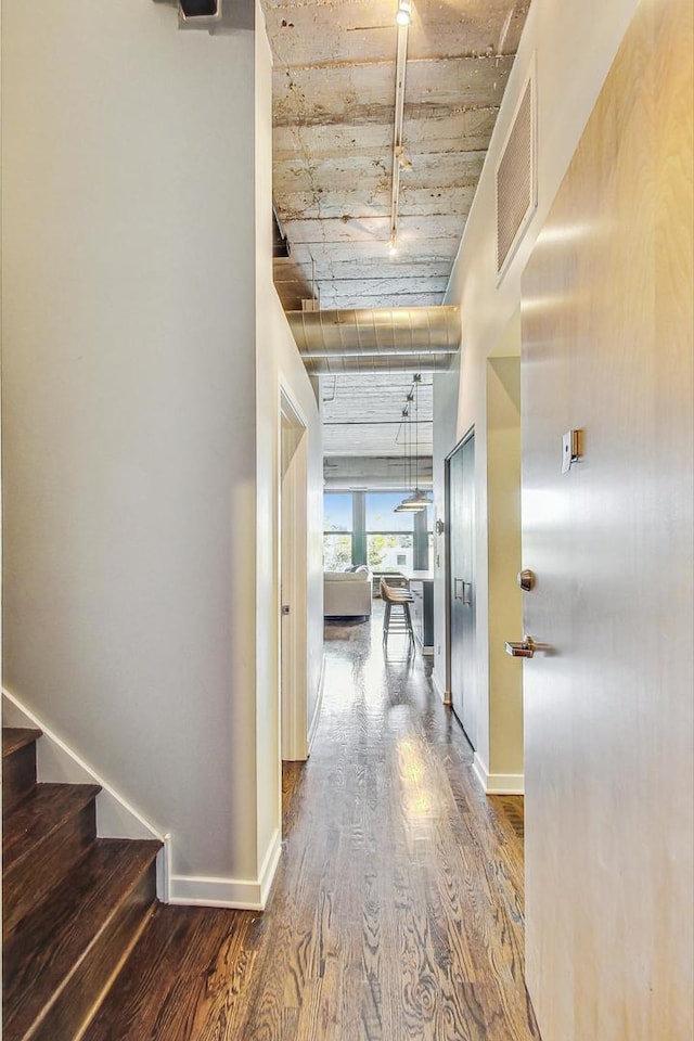 hallway featuring wood finished floors, baseboards, and stairway
