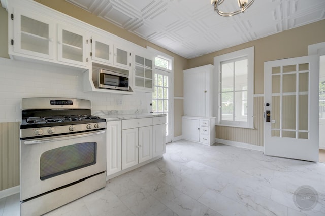 125 Arbor Ave, West Chicago, IL 60185 - kitchen featuring stainless steel appliances, light marble finish floors, white cabinets, decorative backsplash, and glass insert cabinets