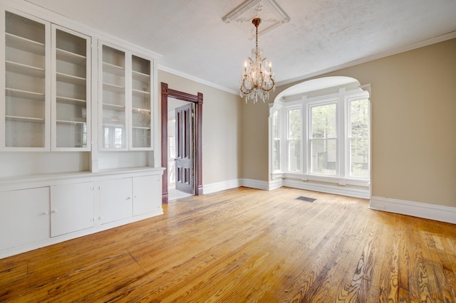 125 Arbor Ave, West Chicago, IL 60185 - unfurnished dining area featuring baseboards, arched walkways, light wood-type flooring, a chandelier, and crown molding